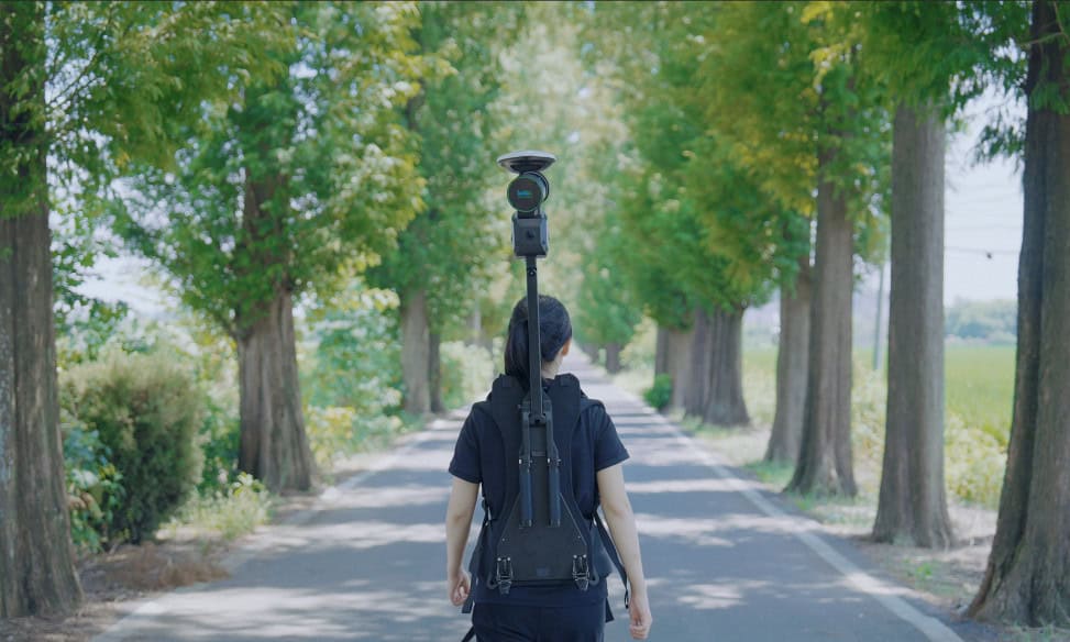 Surveyor using GNSS backpack system for traditional land surveying and topographic data collection