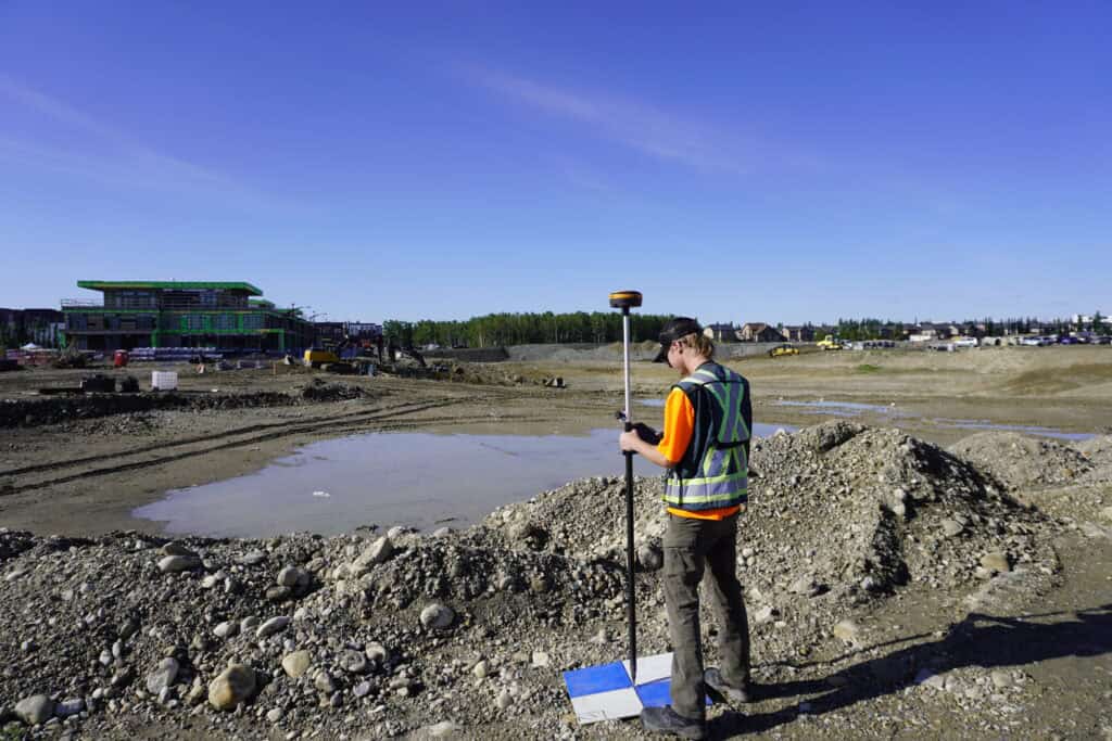 Worker surveying on a gravel site.