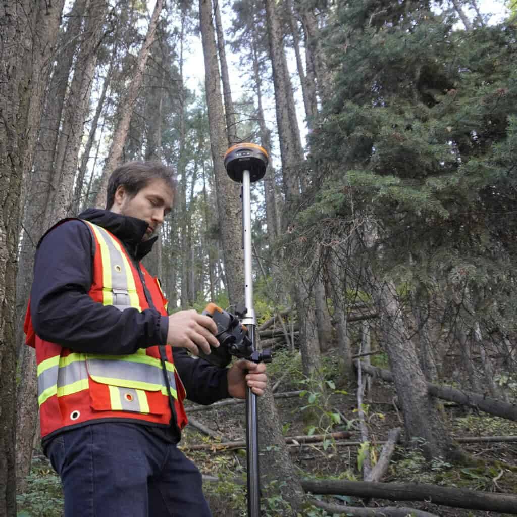 Surveyor in reflective vest using RTK in dense forest