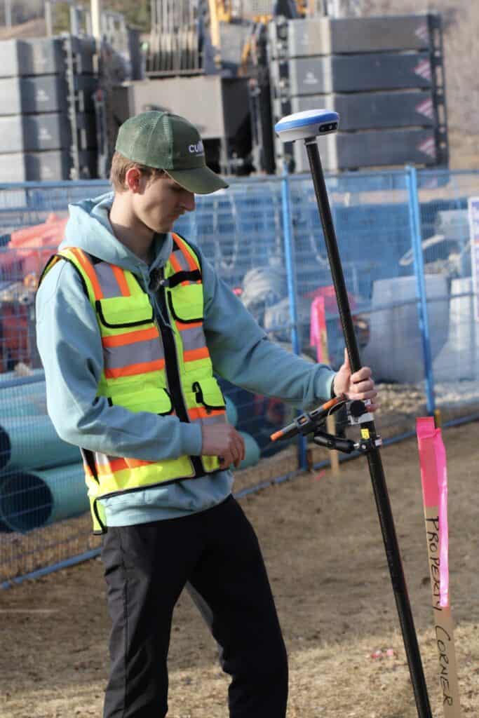 Surveyor using RTK GNSS receiver marking construction layout with flagging