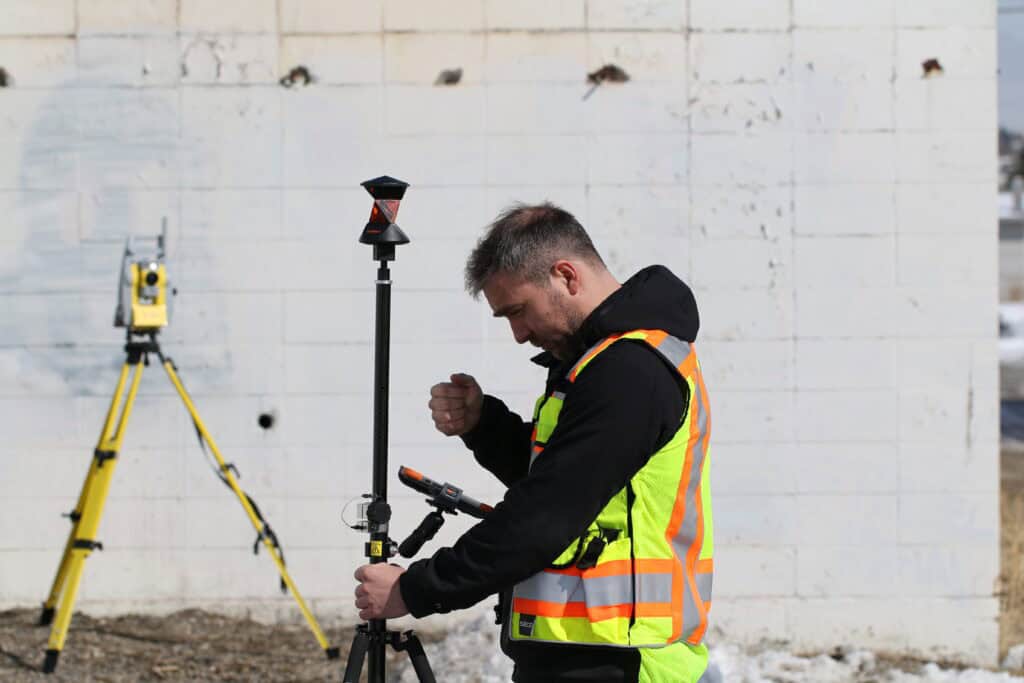 Surveyor using GNSS rover and total station for construction layout work