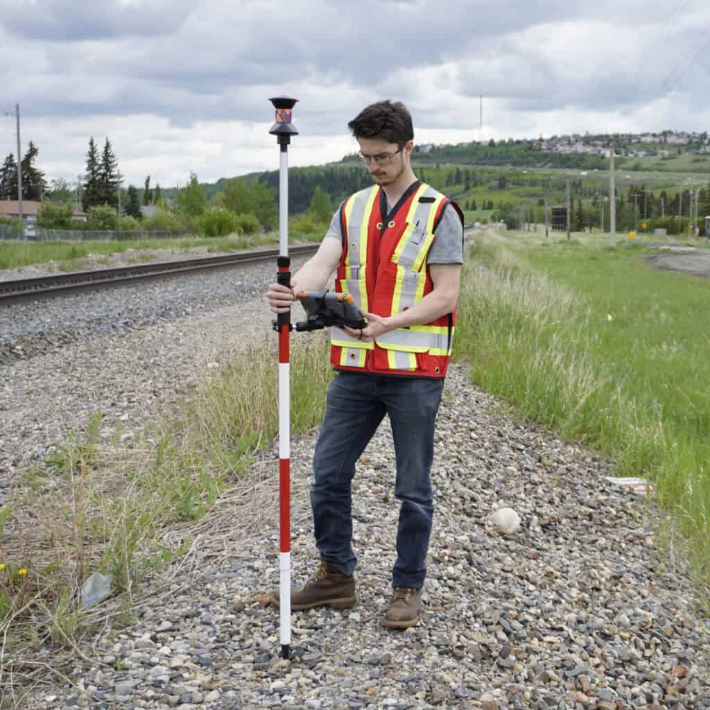 Surveyor using a prism pole with a total station for distance measurement