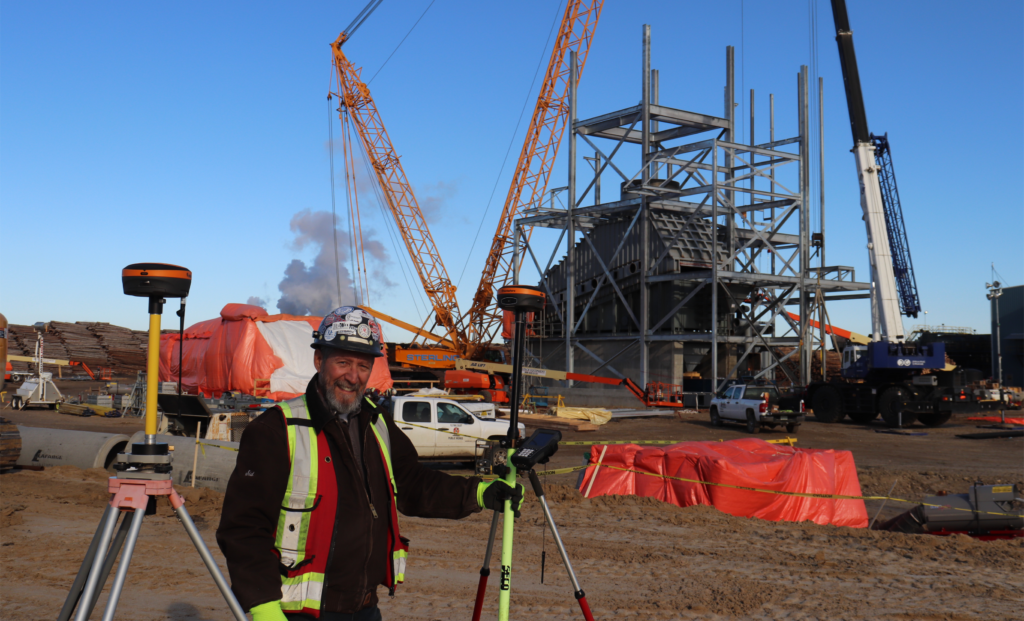 Surveyor using standard GPS receivers on tripods at a construction site